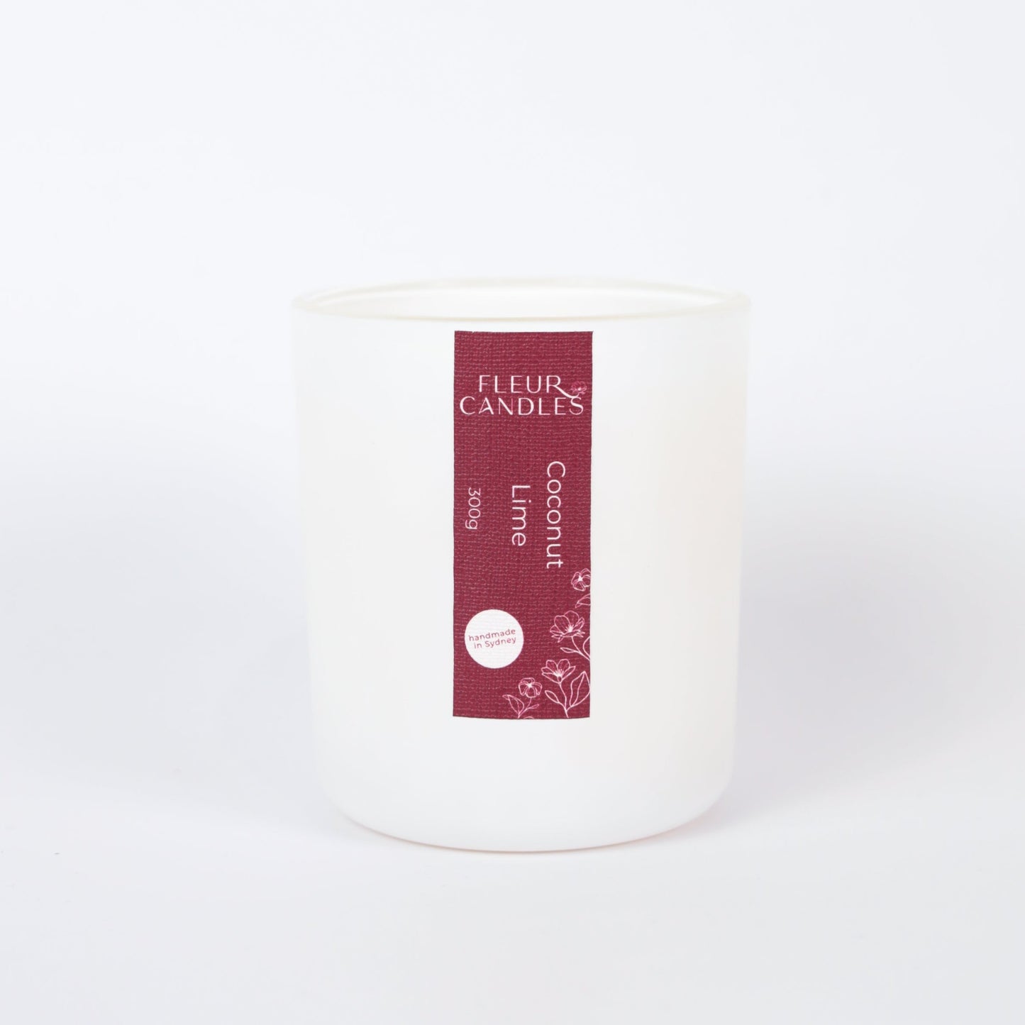 white candle with burgundy label on a white background. fragrance is "coconut lime"