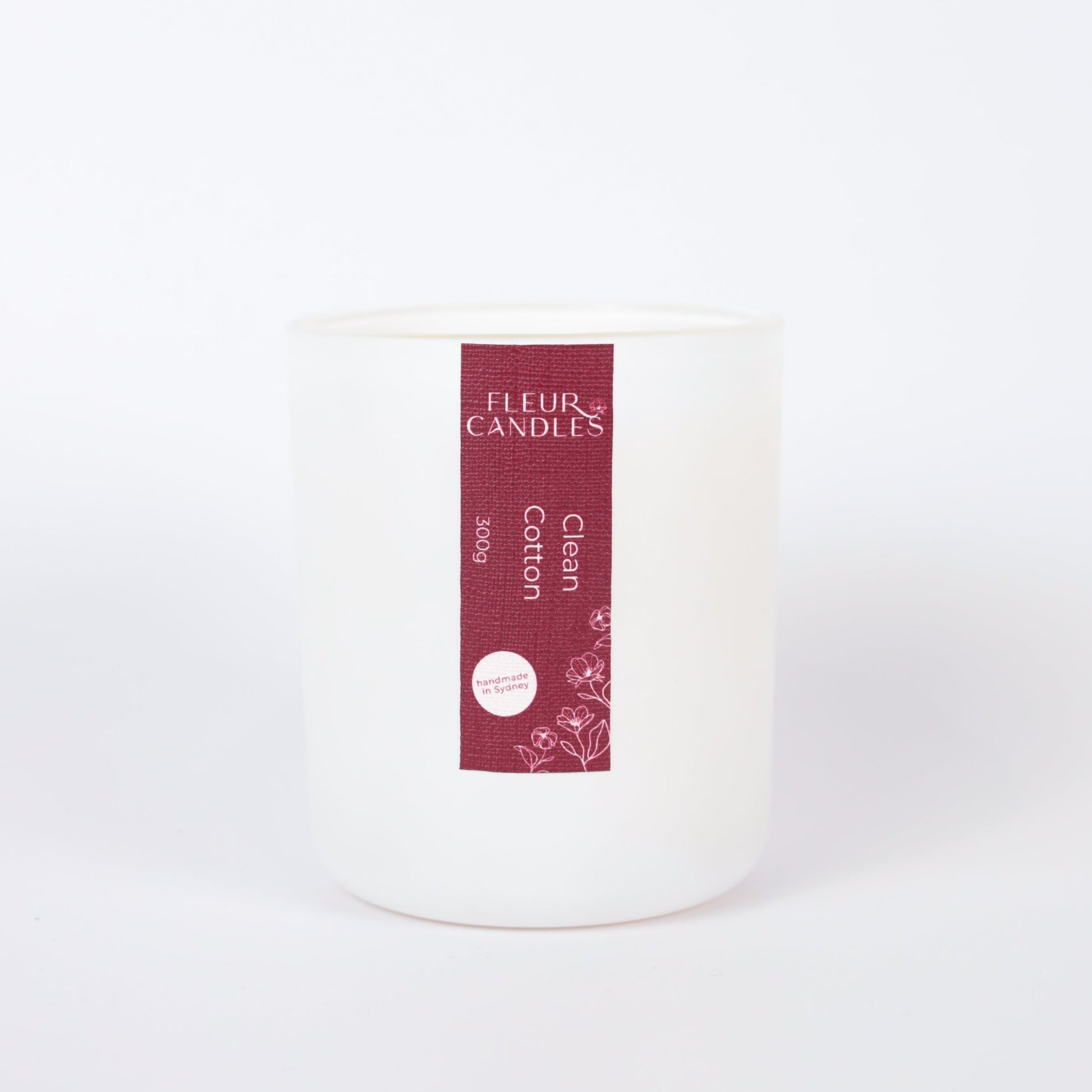 white candle with burgundy label on a white background. fragrance is "clean cotton"